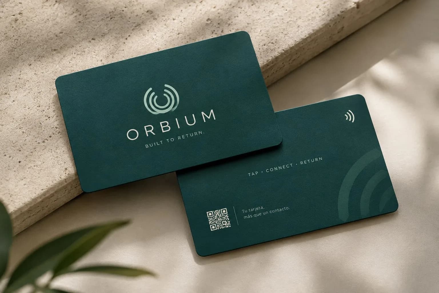 Tarjetas de fidelización Orbium, frente y reverso, en verde pino. El frente lleva el símbolo, la palabra ORBIUM y la frase Built to return; el reverso, un código QR y la leyenda Tap, connect, return.